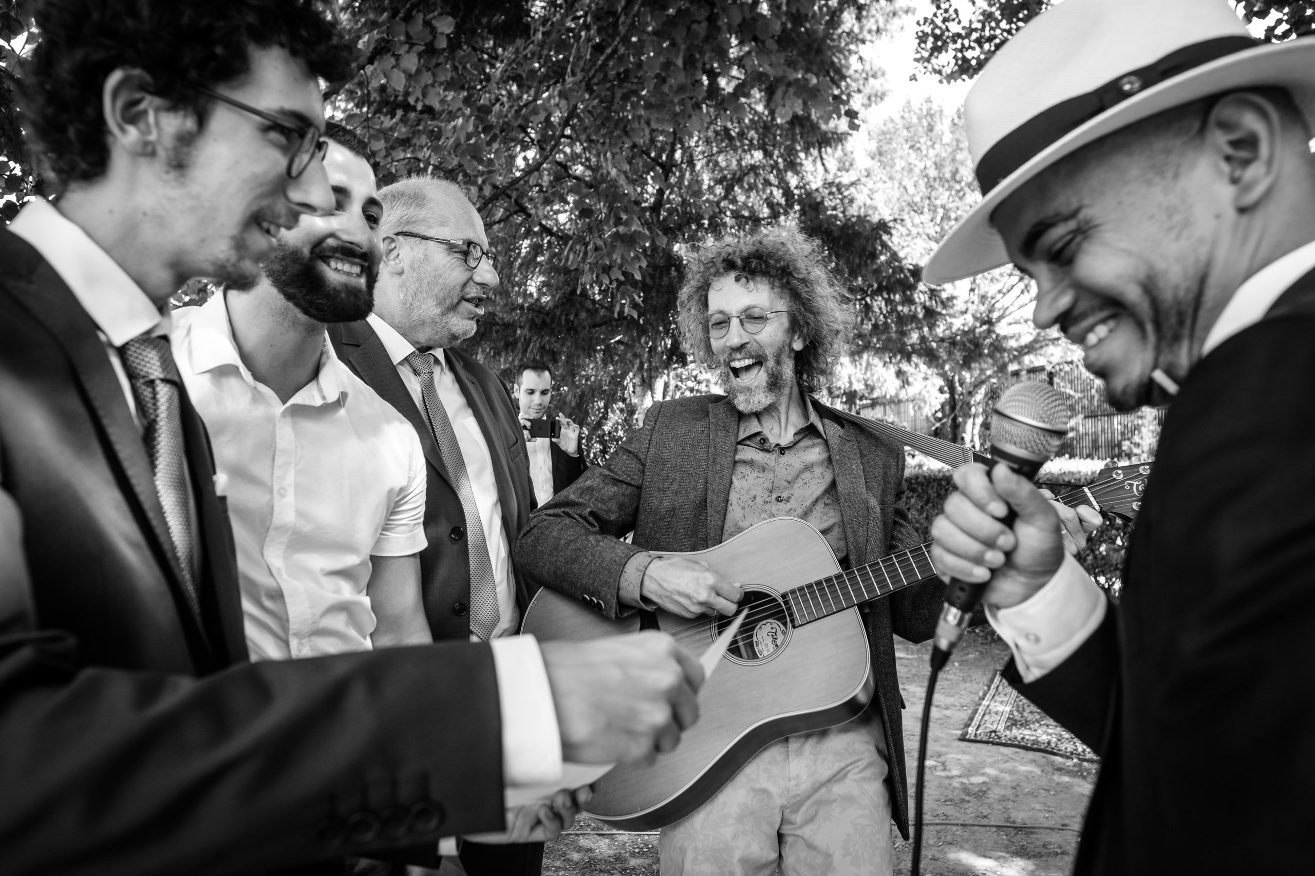 amis du marié réunis autour d'une guitare, photo spontanée en noir et blanc