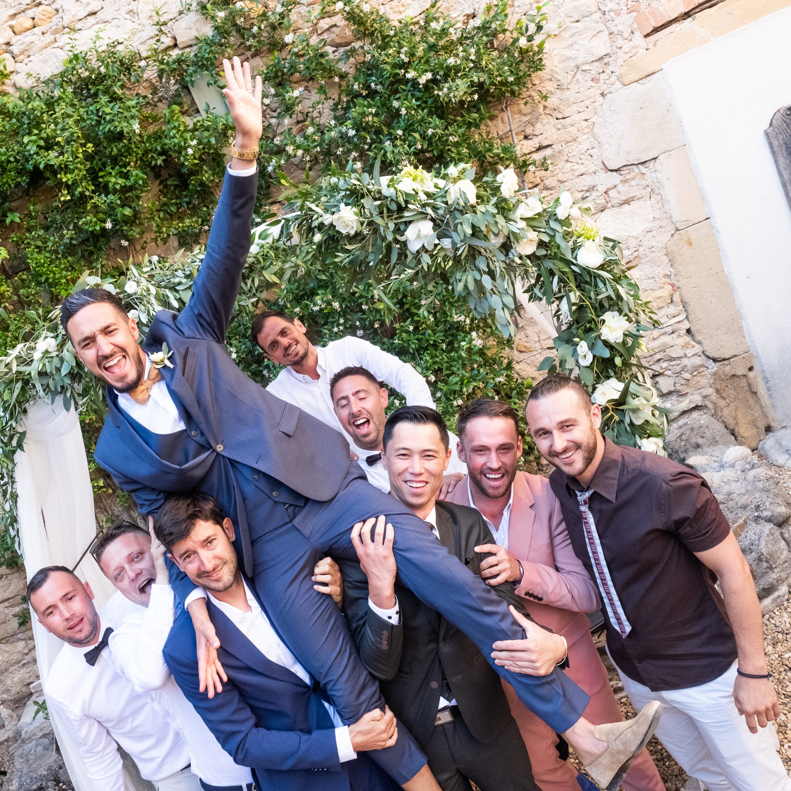 marié porté par ses amis pour une photo de groupe joyeuse dans un jardin