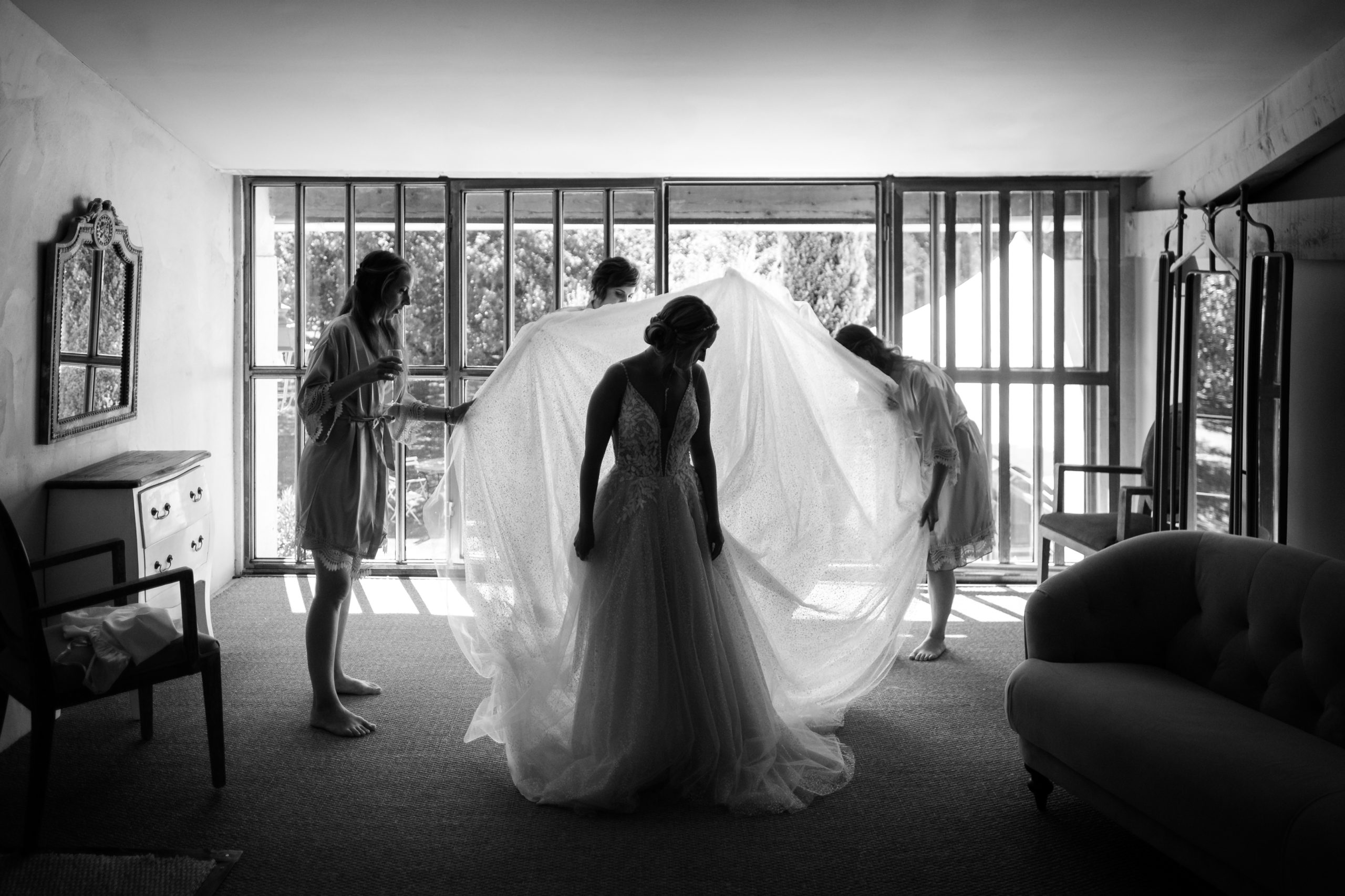 Passage de la robe : deux proches déploient le voile de la mariée devant une grande baie vitrée