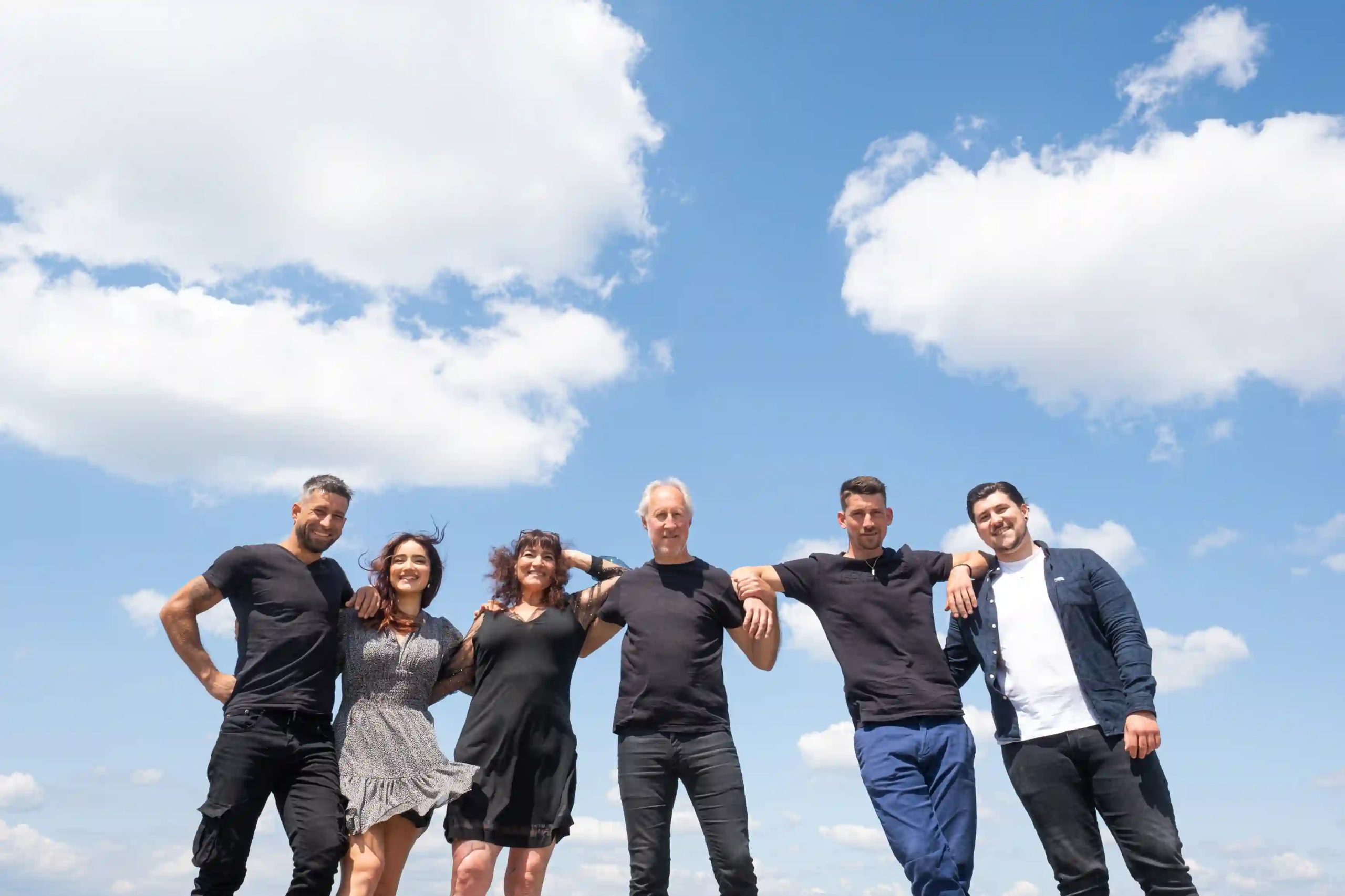 grande famille bras dessus bras dessous sous un ciel bleu, photographe famille en Drôme