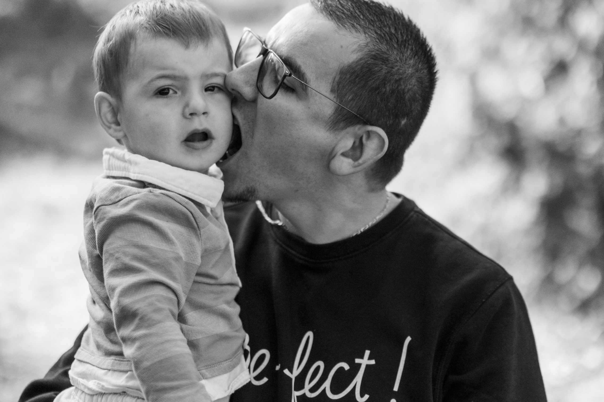 papa embrassant la joue de son petit garçon, portrait de famille en noir et blanc