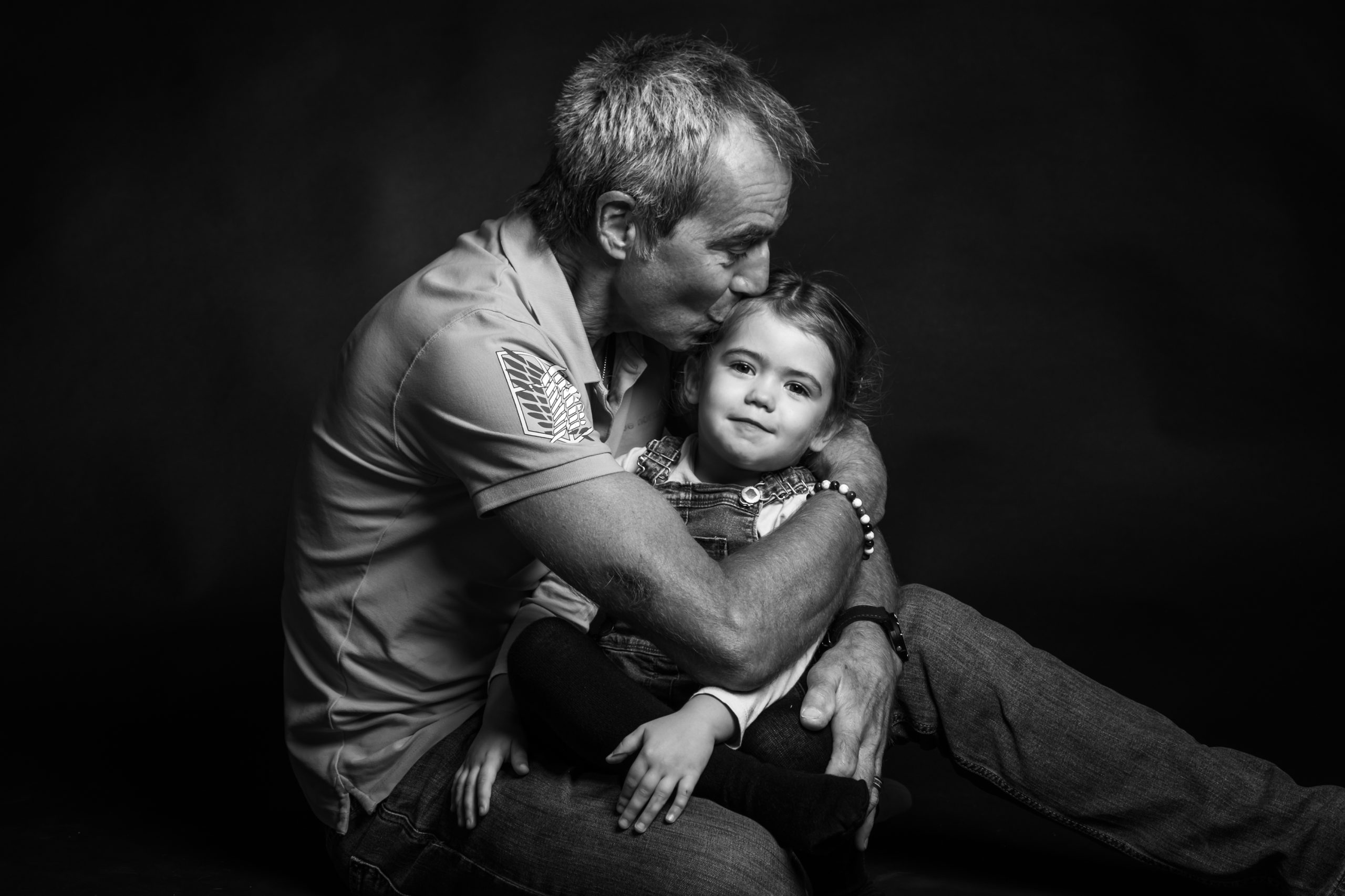 portrait noir et blanc en studio d'un papa serrant sa petite fille dans ses bras