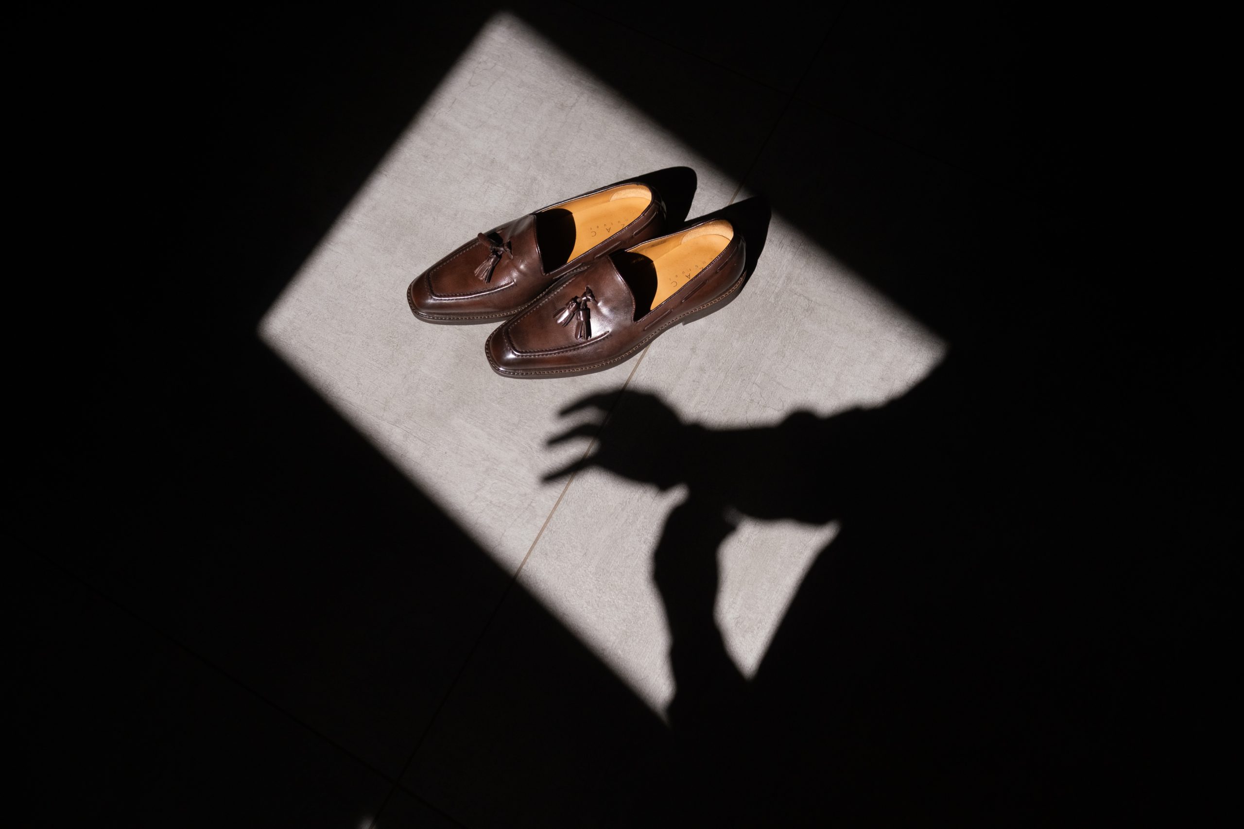 Chaussures du marié posées dans un rai de lumière, détail des préparatifs de mariage photographié en Drôme