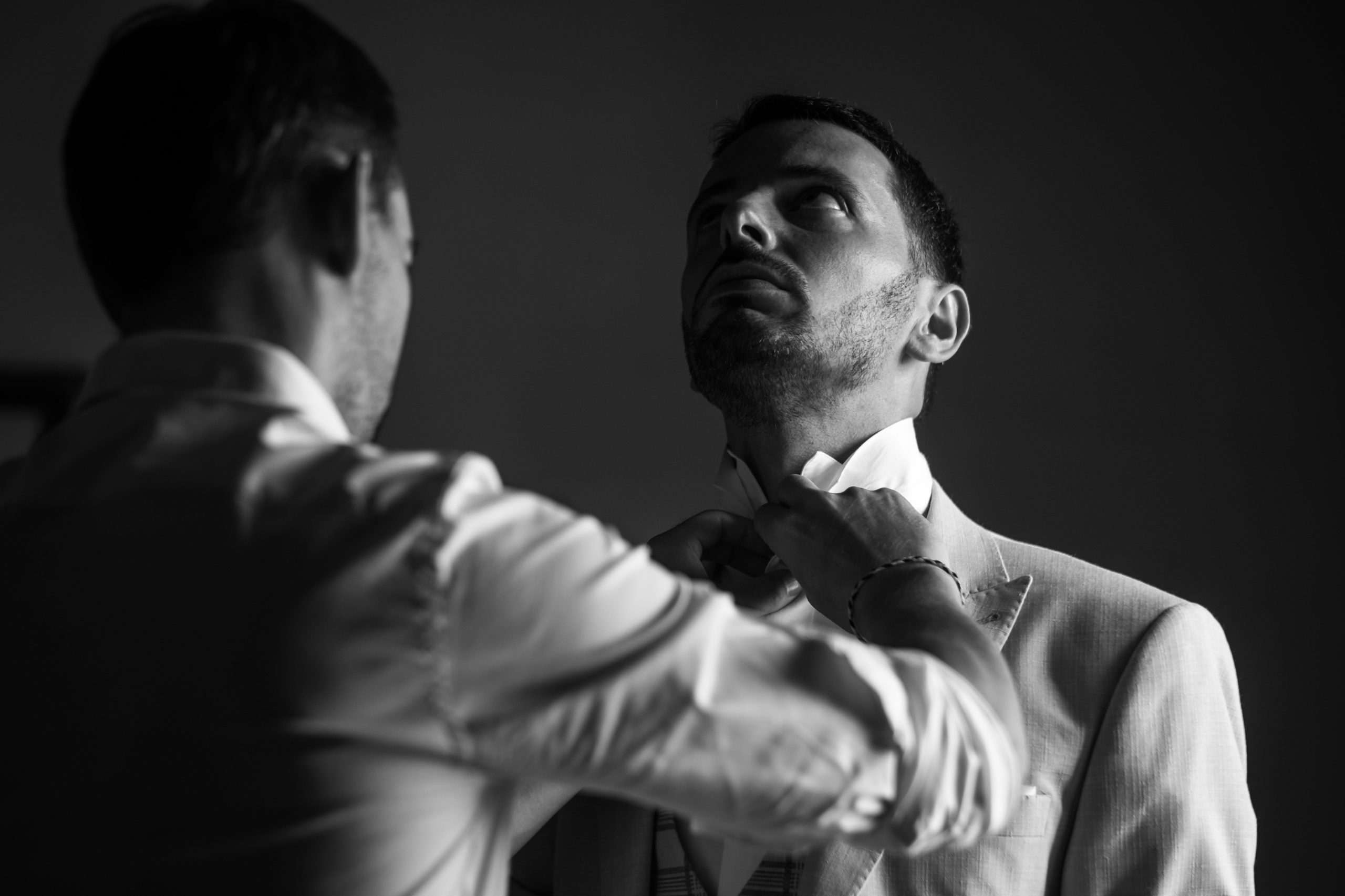 Préparatifs du marié : son témoin ajuste le col de sa chemise, photo en noir et blanc