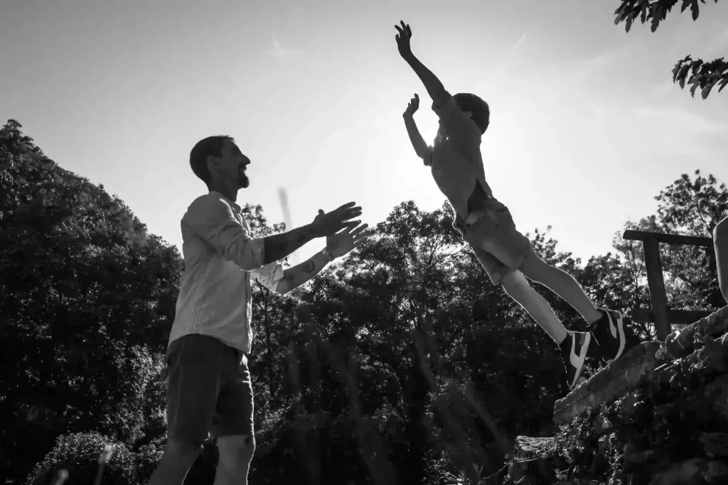 Enfants qui sautent de joie en noir et blanc lors d’une séance photo famille dans la Drôme