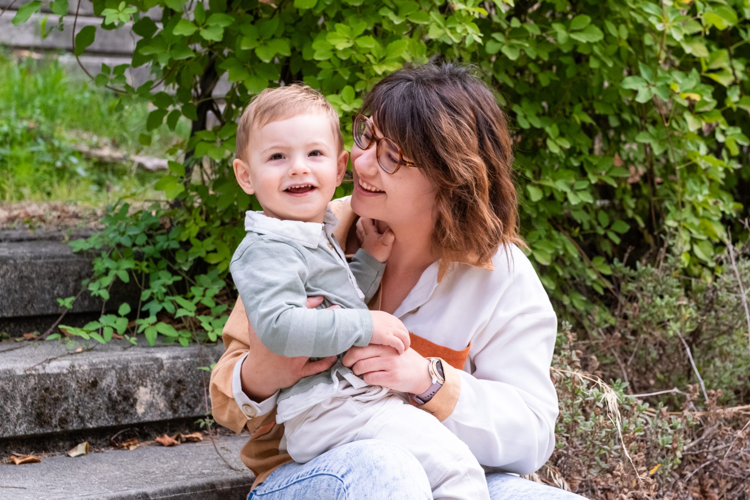 maman et son bébé souriants assis sur des marches en pierre, séance photo famille en Drôme